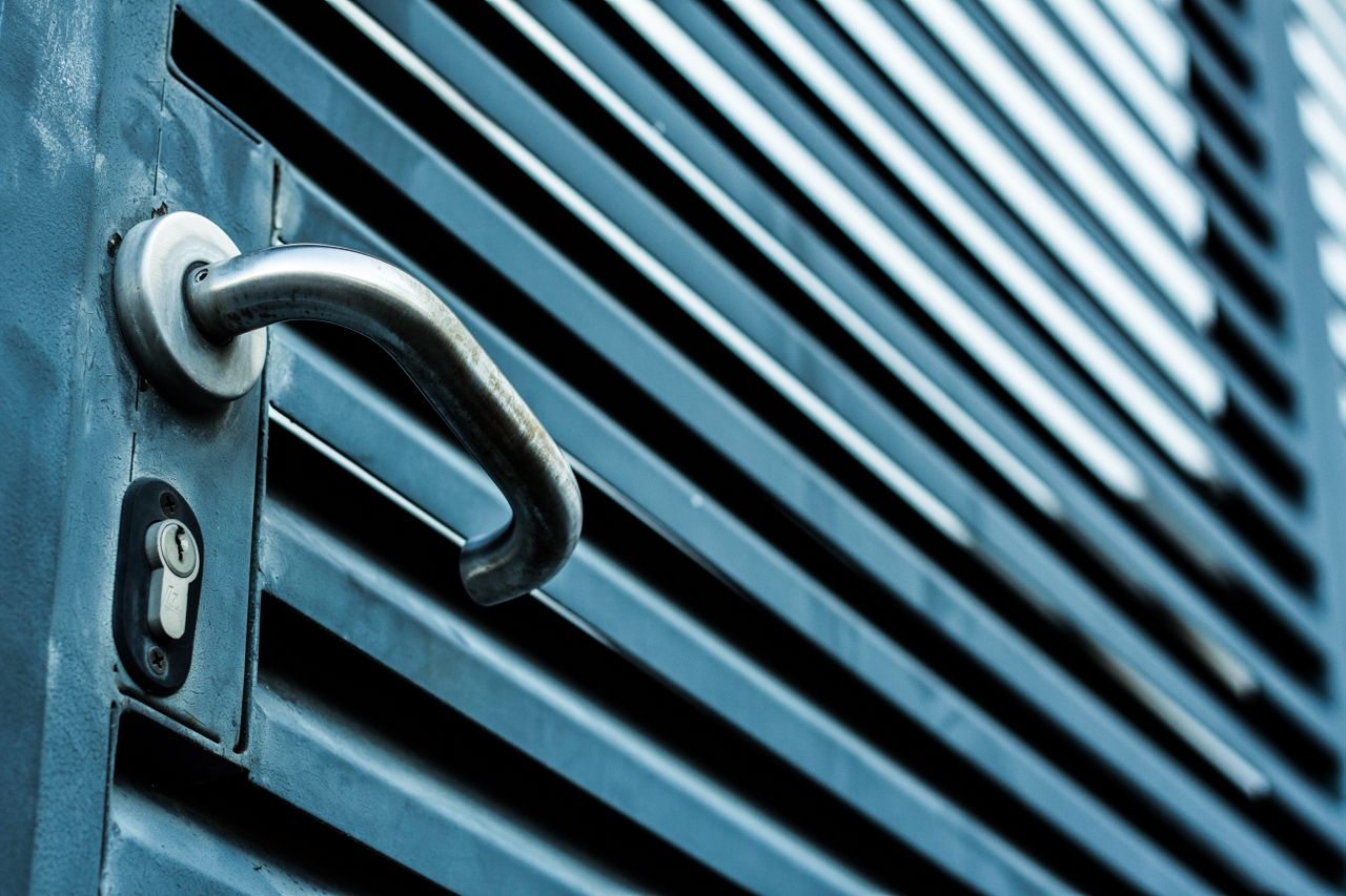 our-value Close-up of a sleek stainless steel door handle and lock on a blue metallic door.